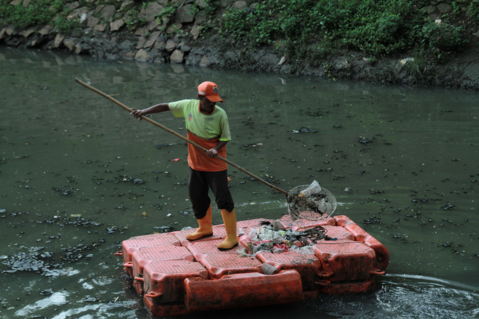 Pekerja Dinas Badan Air Lingkungan Hidup sedang membersihkan sampah dan lumpur di sungai kuningan (Ashar/SinPo.id)